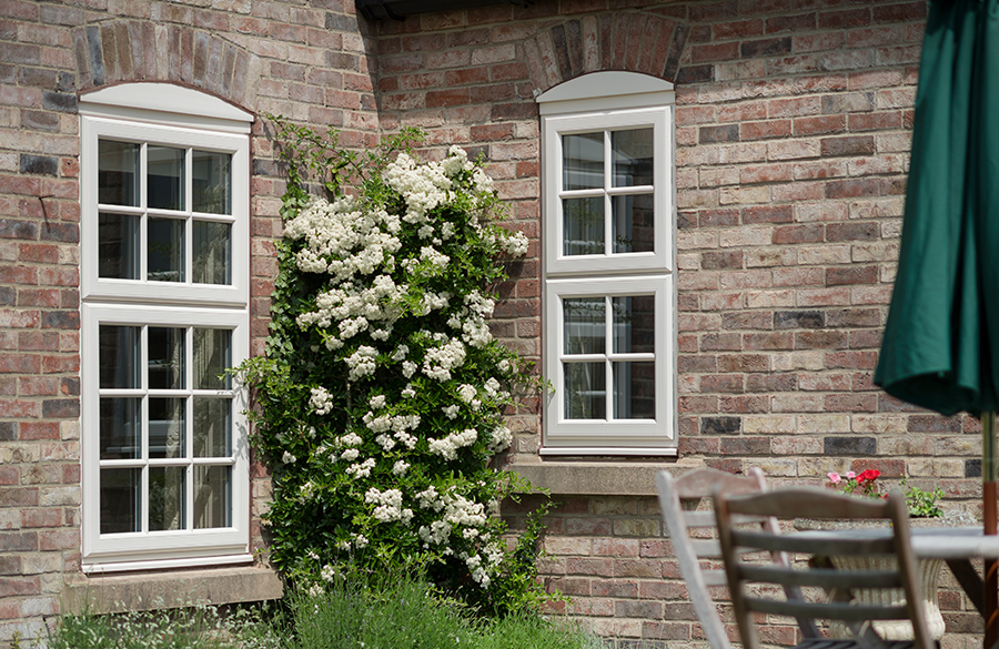 casement windows east sussex in old stone home with table and chairs outside and plant